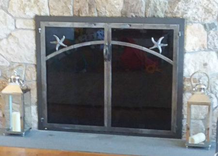 Cotuit fireplace doors black frame with natural iron vice bi fold doors with center forged handles and starfish motif